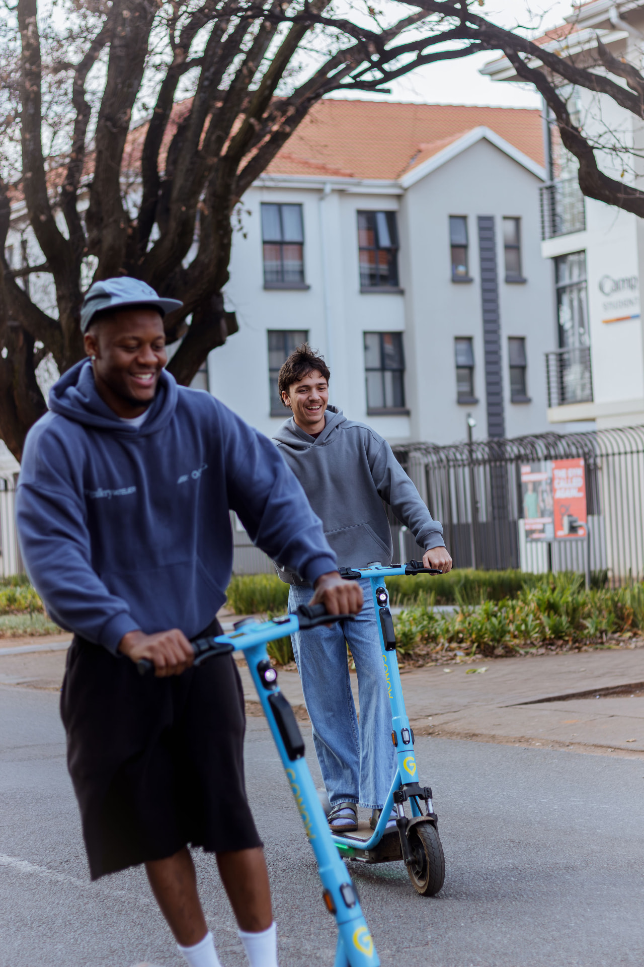 Two riders on GONOW scooters on a Stellenbosch street