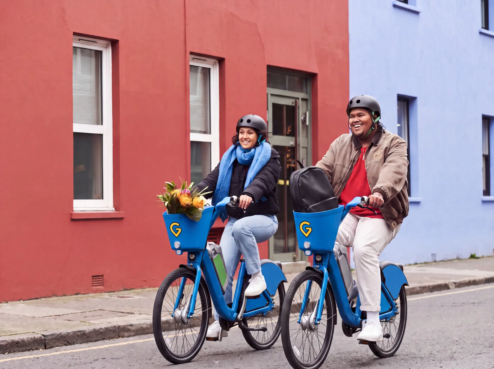 Two smiling riders in helmets on blue GONOW bikes